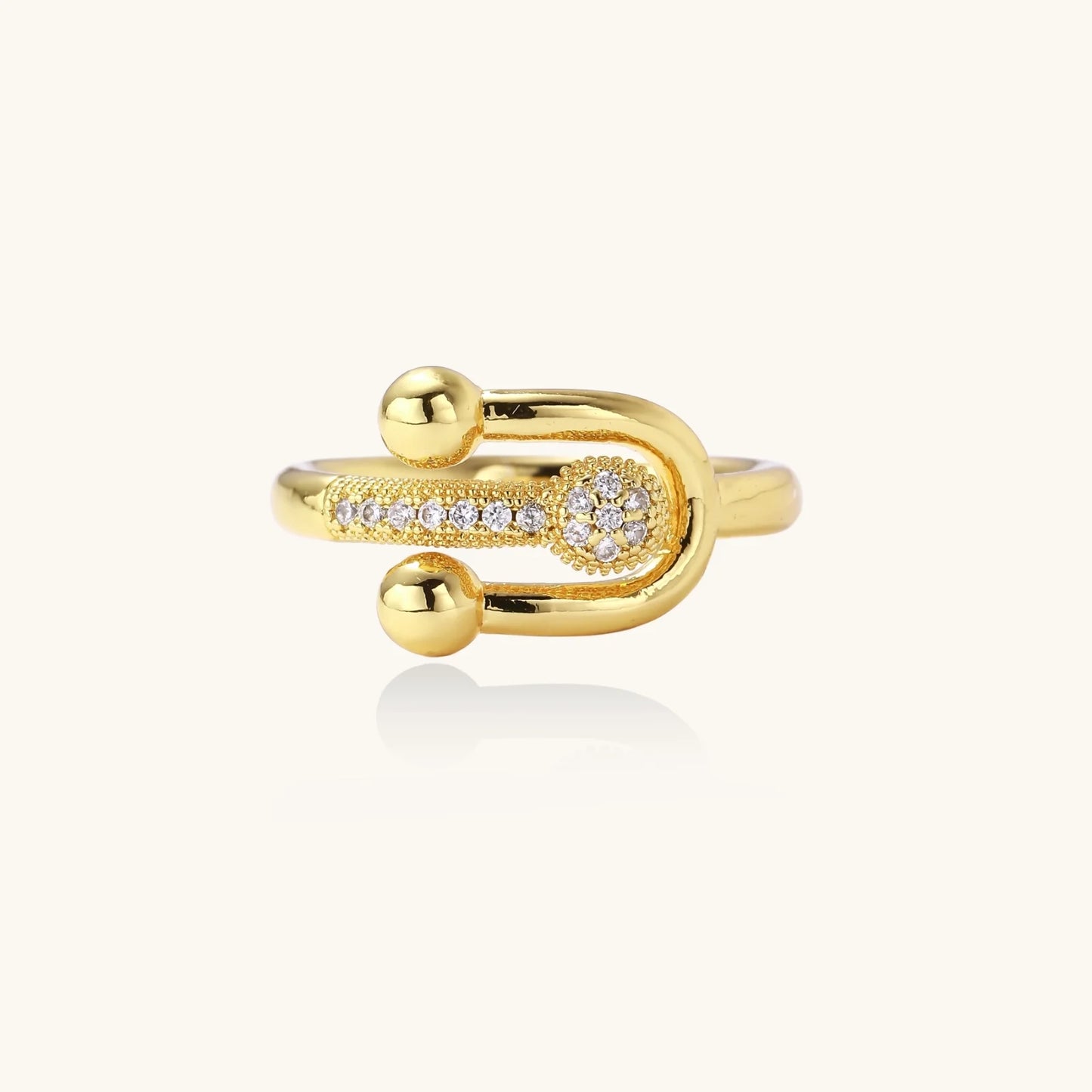 Gold-plated brass ring with safety pin design featuring pavé cubic zirconia stones and dual sphere ends